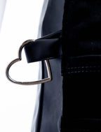 A close-up detail photograph of a silver metal heart-shaped ring attached to a black fabric loop on the side of a professional stylist apron from The Branded Salon.